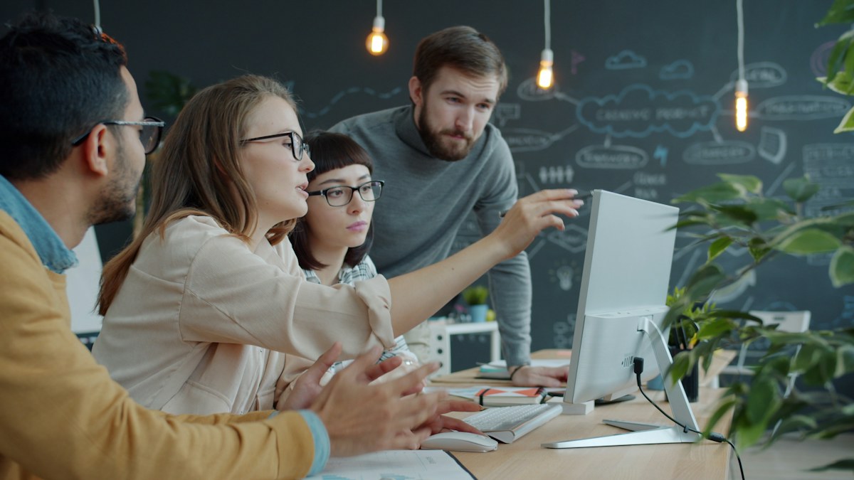 Colleagues discussing a project together around a computer